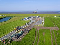 Seekabeleinzug von NordLink unter dem Büsumer Landesschutzdeich. Blick von der landseitigen Kabeleinzugbaustelle zum Büsumer Deich. Mit einer Winde wird das NordLink-Seekabel durch die Leerrohre aus dem Watt unter dem Deich zur Landseite hindurchgezogen